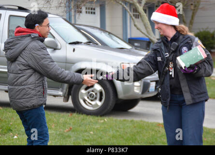 SILVERDALE, Wash. (Dec. 18, 2016) – A Navy Region Northwest (NRNW) Fire and Emergency Services member helps Santa Claus deliver a candy cane to a Naval Base Kitsap (NBK) – Bangor family housing resident. Santa and his helpers delivered candy to NBK residents at Bangor and Jackson Park. Stock Photo