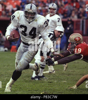 Los Angeles Raiders running back Bo Jackson (34) carries the ball after  taking handoff from quarterback Jay Schroeder (13) against the Kansas City  Chiefs, Sunday, Nov. 25, 1990, in Los Angeles. The