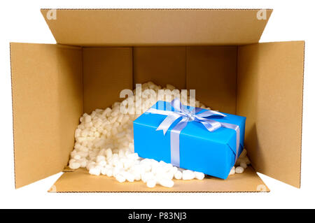 Cardboard shipping delivery box with blue gift inside and polystyrene packing pieces. Stock Photo