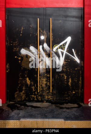 A graffiti-covered black door on a bright red building in Toronto, Ontario, Canada Stock Photo