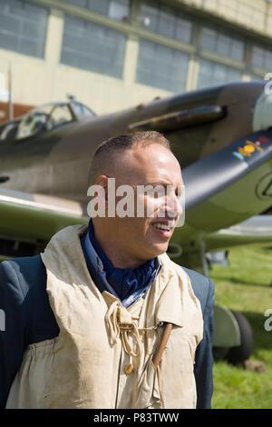 Re-enactor dressed in a world war two period Royal Air Force military uniform and and Mae West life jacket posing in front of Supermarine Spitfire Stock Photo
