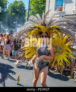 Dancer in flamboyant plumage with a bottle of wine at St Paul's carnival in Bristol UK Stock Photo