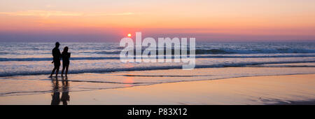 Silhouettes of a couple enjoying the sunset on the atlantic ocean, Lacanau France Stock Photo