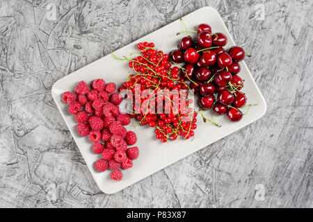 mixed many different colorful seasonal fruits, raspberries, cherries, apricots, on plate, top view, copy space Stock Photo