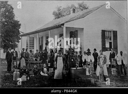 Black and white photograph of Southern University Farm's Dairy Department, comprised by a large group of men and women, some wearing aprons and posing with farm equipment including dairy jugs, with a white, wooden building in the background, located at Southern University in New Orleans, Louisiana, 1893. Courtesy Internet Archive. () Stock Photo