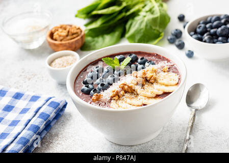 Acai blueberry smoothie bowl with superfood toppings on bright gray concrete background. Selective focus Stock Photo