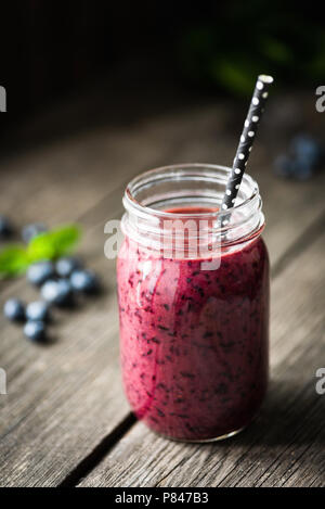 Vegan acai blueberry smoothie in bottle on wooden table, selective focus Stock Photo