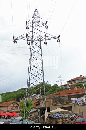 Electrical towers with wires for electricity in the center of the city. Electrical towers between houses. Metal poles of power lines. High-voltage dir Stock Photo