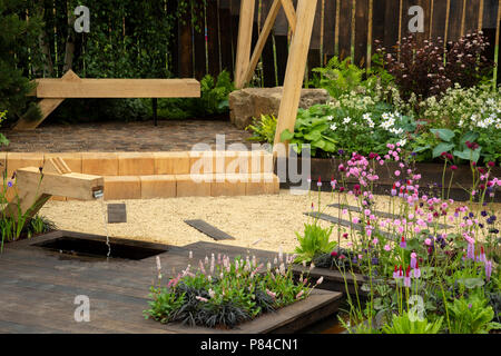 Colourful flowers, timber bench, path & pond in beautiful prize-winning show garden, The Great Outdoors - RHS Chatsworth Flower Show, England, UK. Stock Photo