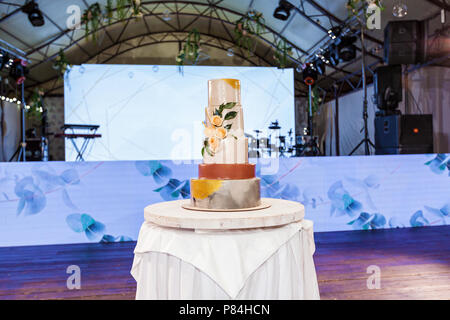 Large multicolored multi-colored wedding cake with roses on a round wooden stand Stock Photo