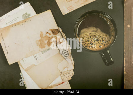 Coffee mug near old postal cards Stock Photo