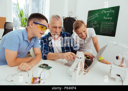 Smart science teacher pointing at the robot Stock Photo