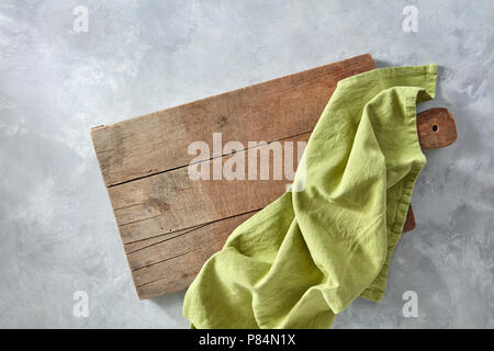 A wooden board with a green kitchen napkin on a gray concrete background with a copy space. Top view Stock Photo