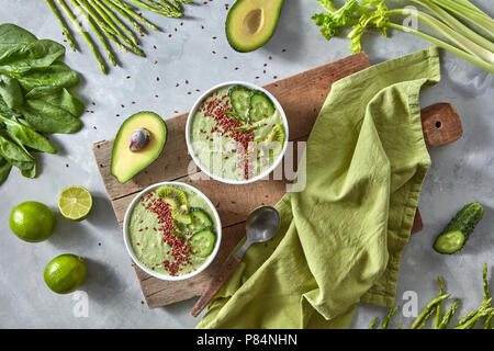Green smoothies from avocado with cucumber, kiwi and flax in a plate on a wooden board on a gray concrete background. Healthy food Stock Photo