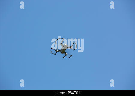 A camera carrying drone flying in a clear blue sky Stock Photo