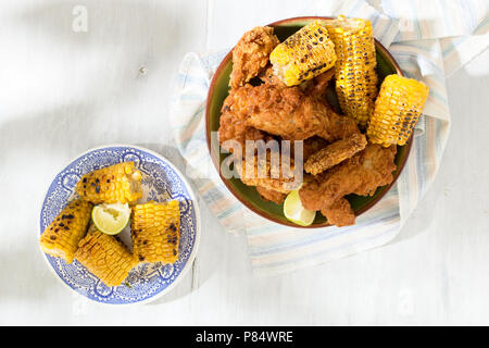 Fried chicken legs with grilled corn on white wooden table, top view Stock Photo