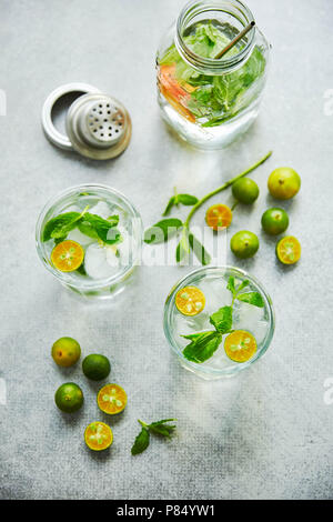 Gin and tonik cocktail with green calamondin and fresh mint leaf. Vertical top view. Stock Photo