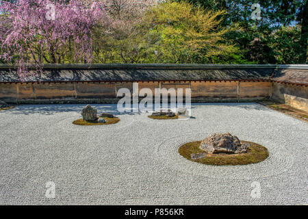 Japanese tourists enjoy tranquility at Ryoanji Temple in Kyoto, Japan. This Zen Buddhist temple is famous for its rock garden. Stock Photo