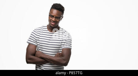 Young african american man wearing glasses and navy t-shirt happy face smiling with crossed arms looking at the camera. Positive person.