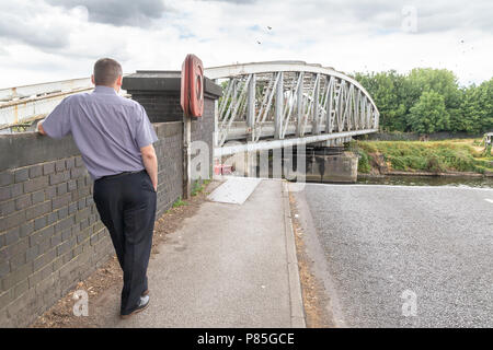 09-July 2018 - Male pedestrian leans against a wall and watches as Stockton Heath Swing Bridge closes after a ship has passed along the Manchester Shi