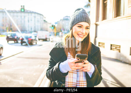 young woman outdoor using smart phone hand hold smiling - technology, happiness, social network concept Stock Photo