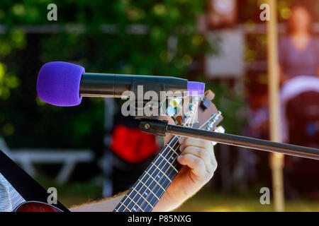 male musician playing acoustic guitar behind condenser microphone in recording microphone musician Stock Photo