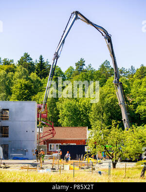 Builders working with very large crane pouring concrete at construction site Stock Photo