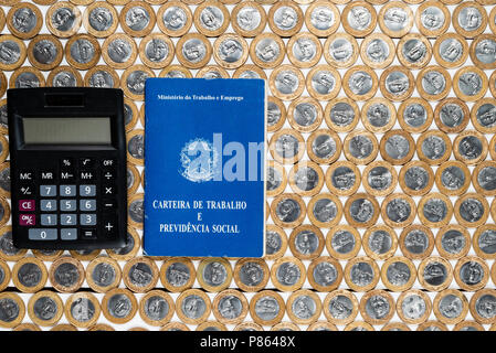 Work permit and black calculator on several Brazilian one real coins Stock Photo