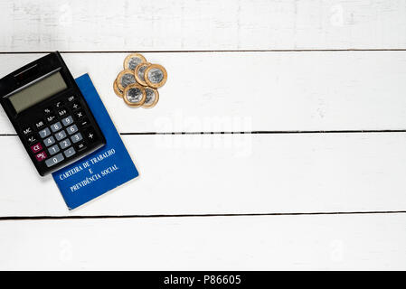 Work permit, black calculator and some Brazilian one real coins on white background Stock Photo