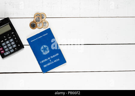 Work permit, black calculator and some Brazilian one real coins on white background pinus Stock Photo