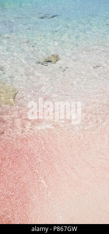 Full frame cristal clear water in a beach with pink sand at shore Stock Photo