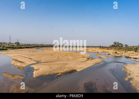 Indian river with clean water in sandy bed  with power grid cable laying background. Stock Photo