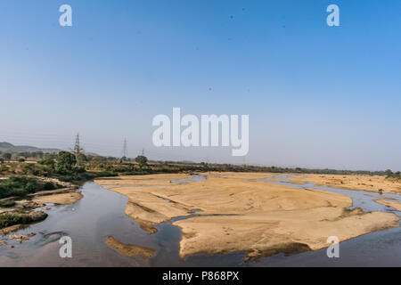 Indian river with clean water in sandy bed  with power grid cable laying background. Stock Photo