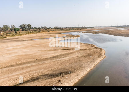 Indian river with clean water in sandy bed  with power grid cable laying background. Stock Photo