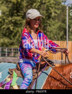 Attractivr, young girl, sitting in the saddle, big smile on her face, enjoying horseback riding and trail ride adventure. Stock Photo