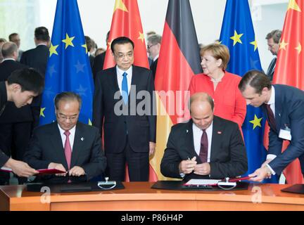 Berlin, Germany. 9th July, 2018. Chinese Premier Li Keqiang (L, back) and German Chancellor Angela Merkel (R, back) witness the signing of bilateral cooperation documents after the fifth round of intergovernmental consultations, co-chaired by the two leaders, in Berlin, Germany, July 9, 2018. Credit: Li Tao/Xinhua/Alamy Live News Stock Photo