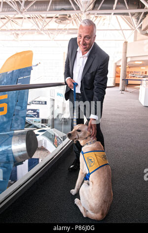 Garden City, New York, USA. 21st June, 2018. NASA space shuttle astronaut MIKE MASSIMINO poses with dog from Canine Companions for Independence, a Medford organization, brought by Volunteer Puppy Raiser Florence Scarinci, after the museum's Members Meet & Greet before Massimino's free lecture in JetBlue Sky Theater Planetarium at the Cradle of Aviation's Museum, part of the museum's Countdown to Apollo at 50, celebrating 50th anniversary of Apollo 11 moon landing on July 20, 1969. Credit: Ann Parry/ZUMA Wire/Alamy Live News Stock Photo