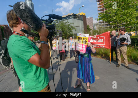London, UK. 9th July 2018. A woman holds up a 'No To Trump' poster in front of a hostile right-wing cameramanwho had tried to interrupt the first protest in the week of action against President Trump's visit outside the US Embassy in Nine Elms hosted by Momentum Wandsworth. Speakers reminded us that in addition to all his other faults, Trump has described Wandsworth where the new embassy is as 'lousy' and 'horrible'. Wandsworth has a long and proud radical tradition, and the embassy site was the home of one of the leading suffragettes, Charlotte Despard. Two Labour councillors were among the s Stock Photo