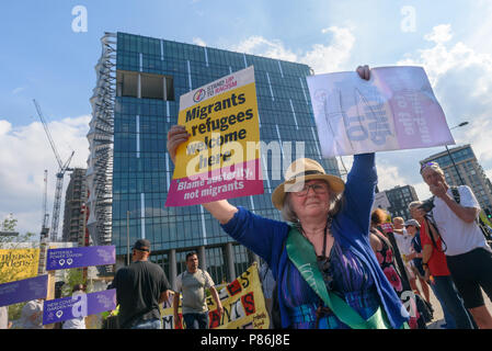 London, UK. 9th July 2018. A woman holds up posters to passing drivers at the first protest in a week of action against President Trump's visit outside the US Embassy in Nine Elms hosted by Momentum Wandsworth. Speakers reminded us that in addition to all his other faults, Trump has described Wandsworth where the new embassy is as 'lousy' and 'horrible'. Wandsworth has a long and proud radical tradition, and the embassy site was the home of one of the leading suffragettes, Charlotte Despard. Two Labour councillors were among the speakers but local Labour MP Marsha De Cordova who had hoped to b Stock Photo