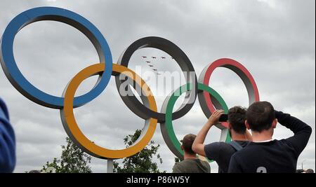 Stratford, London, UK. 10th July, 2018. The Red Arrows fly over the Olympic rings. Royal Air Force (RAF) 100 years celebration flypast. Queen Elizabeth Olympic Park. Stratford. London. UK. 10/07/2018. Credit: Sport In Pictures/Alamy Live News Stock Photo