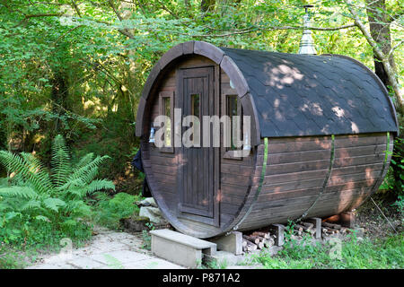 Exterior view of a wooden barrel shaped sweat lodge in a woodland landscape by a stream for bathing in a rural Welsh valley Wales UK  KATHY DEWITT Stock Photo