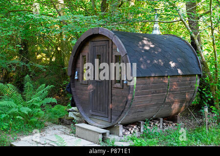 Exterior view of a wooden barrel shaped sweat lodge in a woodland landscape by a stream for bathing in a rural Welsh valley Wales UK  KATHY DEWITT Stock Photo