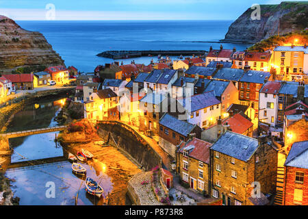 Blue hour over the beautiful village of Staithes on the Yorkshire coast in Northern England.  Once the sun goes down the lights on the houses come on. Stock Photo
