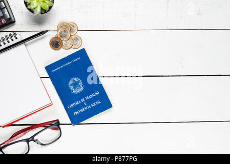 Work permit, cactus, notepad, black pencil,  glasses, calculator and some Brazilian one real coins on white background pinus Stock Photo