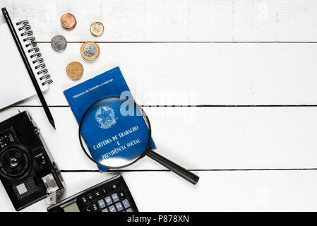 Work permit, camera, calculator, notepad, black pencil, magnifying glasses,  and some Brazilian coins on white background pinus Stock Photo