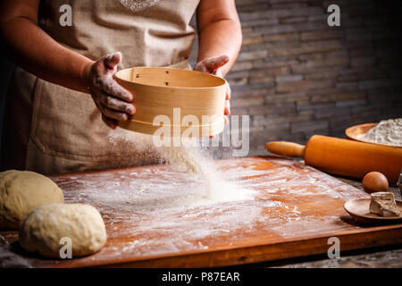 Woman hands sifting flour with flour filter Stock Photo