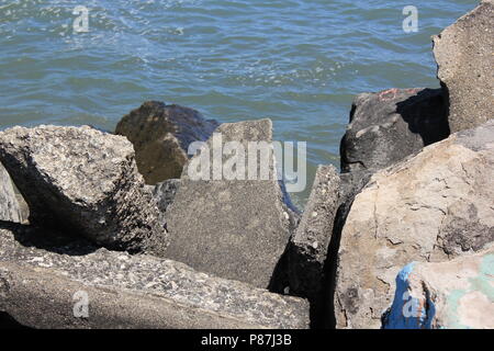 Broken rocks at the lakefront at Northwestern University Park on the Lake in Evanston, Illinois on a beautiful sunny summer day. Stock Photo