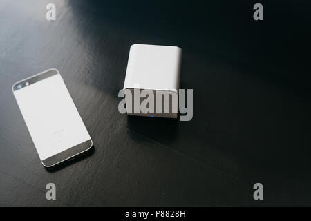 Wireless speakers and a cell phone next to them on a dark background. Modern technology for listening to music from a mobile phone. Stock Photo