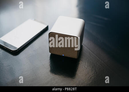 Wireless speakers and a cell phone next to them on a dark background. Modern technology for listening to music from a mobile phone. Stock Photo