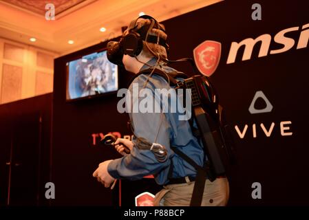CES (Consumer Electronics Show) trade show attendee trying out game with wearable MSi computer-in-backpack with HTC Vive virtual reality VR  headset. Stock Photo